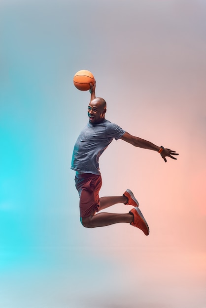 Basketball player in action full length of young african sportsman playing basketball and jumping