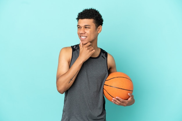 Basketball player African American man isolated on blue background looking to the side and smiling