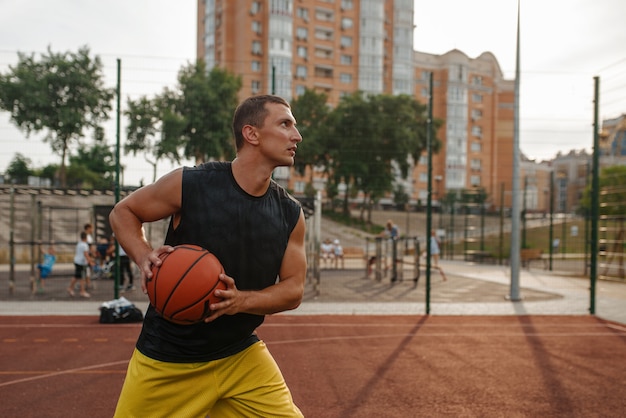 Basketball player prepares to make a shoot on outdoor court.