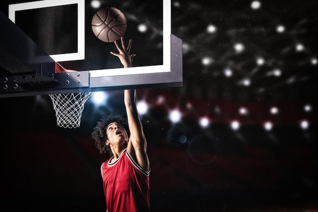 Basketball player in red uniform jumping high to make a slam dunk to the basket