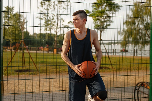 Basketball player standing at the mesh fence