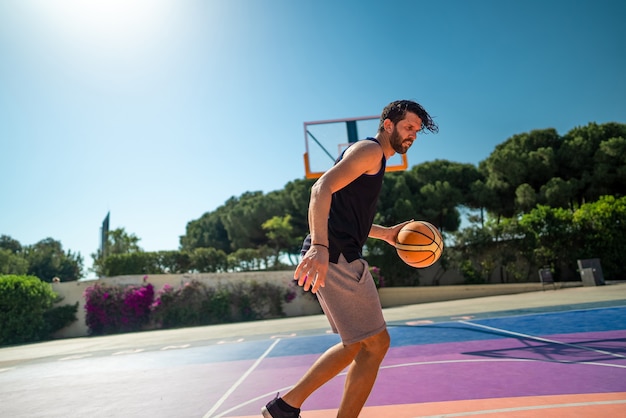 Basketball player trains himself on a basketball court with a ball