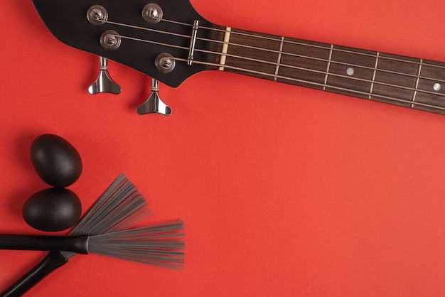 Bass guitar neck shakers and drum brushes on a bright red background Top view flat lay space for