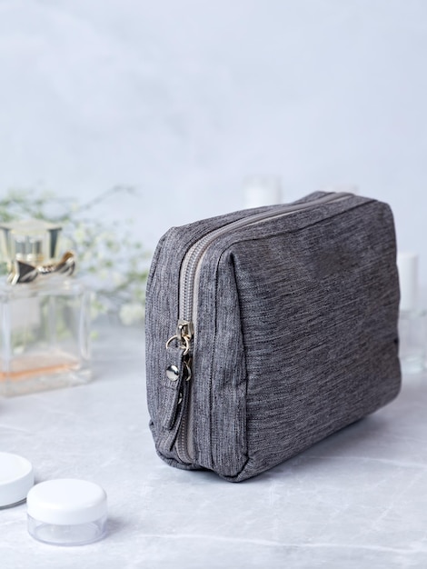 Bath accessories toilet bag Gray cosmetic bag with zipper with flowers and perfume in the background