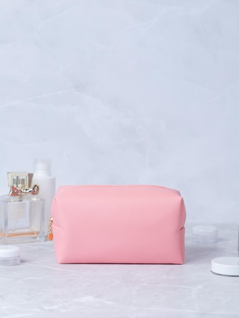 Bath accessories toilet bag Pink leather cosmetic bag with zipper with flowers and perfume in the background