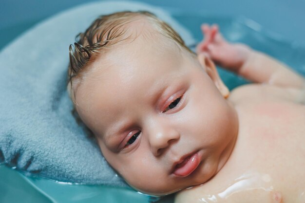 Bathing a baby in a baby bath The first bath of a newborn baby A baby bathes in a bath with water Personal hygiene of a newborn