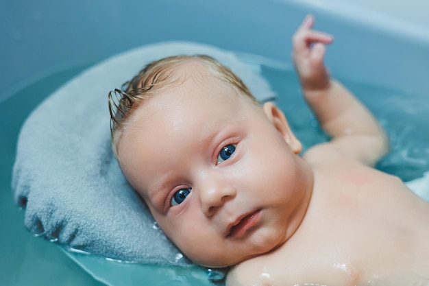 Bathing a baby in a baby bath The first bath of a newborn baby A baby bathes in a bath with water Personal hygiene of a newborn