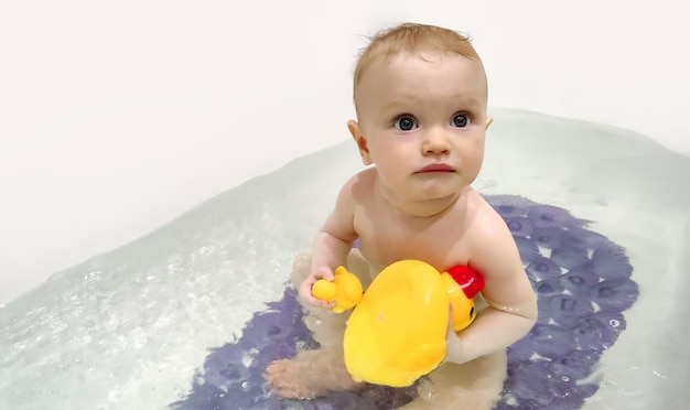 Bathing a baby in a bathtub in clean water girl playing with ducksxA