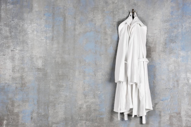 Bathrobes hanging on grey wall