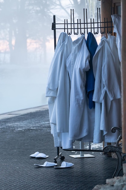 Bathrobes towels hang on rack hanger standing outside near entrance of heated winter opening pool