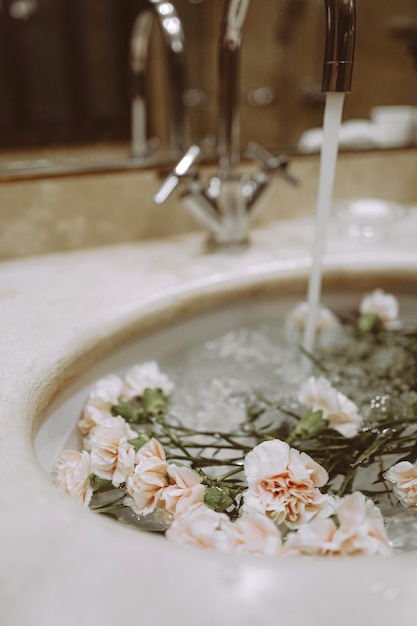 Bathroom interior details with flowers in the sink. Aesthetic beauty