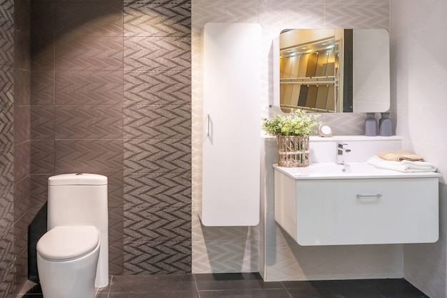 Bathroom interior with white wall, vintage furniture, towels, toilet and sink