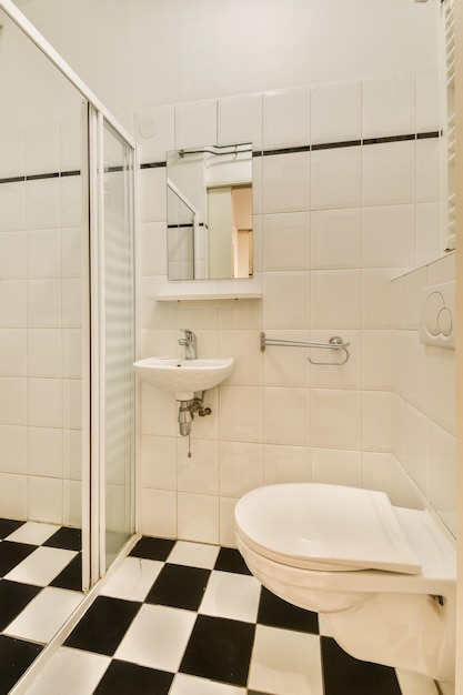 A bathroom with black and white checkered tiles on the floor shower stall and toilet in the corner area