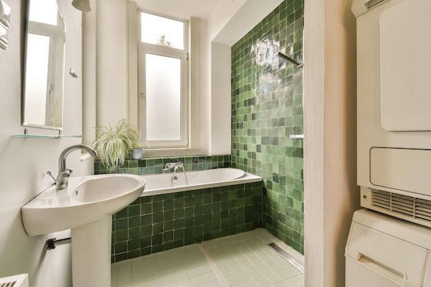 A bathroom with green tile and a tub and sink