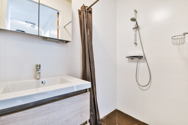 Bathroom with white tiled walls and open shower near sink base cabinet in light