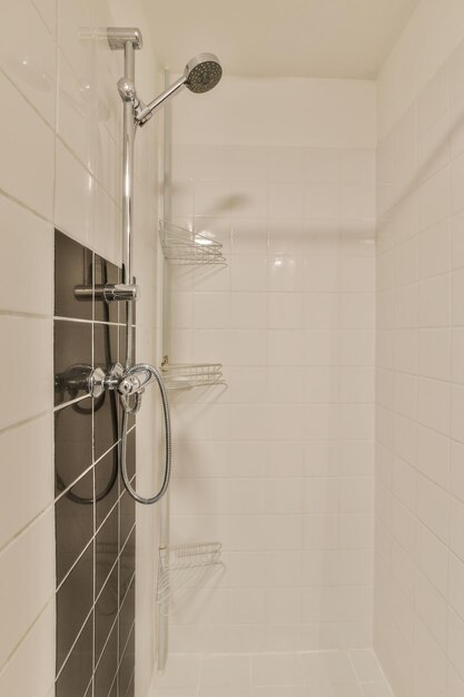 A bathroom with white tiles and black shower headphones on the wall above it is an image of a walk in shower