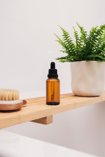 Bathtub wooden tray with beauty cosmetic oil bottle and accessories in a modern interior scandinavian bathroom with white tiles as a background Home decor with wooden bath tray green plantsxA