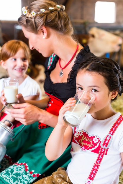 Bavaria family drinking milk in cow barn 