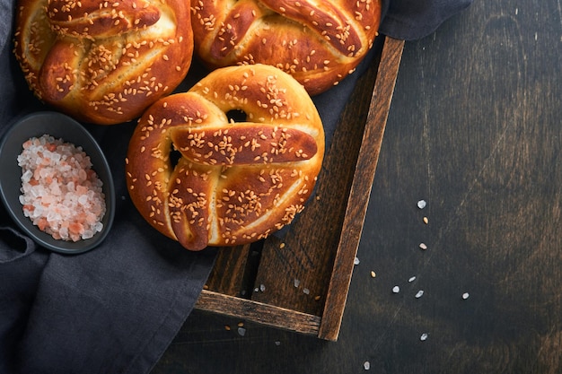 Bavarian pretzels and glass of lager beer Oktoberfest food menu traditional salted pretzels over old dark wooden background Top view with space for text Oktoberfest theme