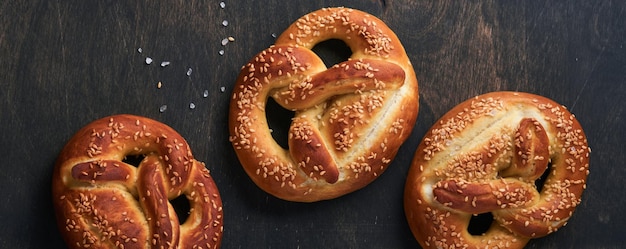 Bavarian pretzels and glass of lager beer Oktoberfest food menu traditional salted pretzels over old dark wooden background Top view with space for text Oktoberfest theme