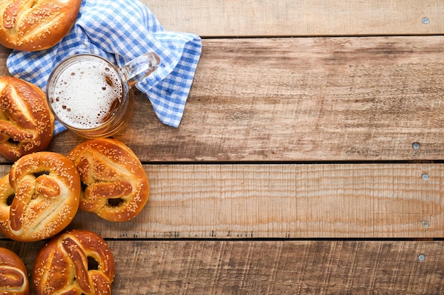 Bavarian pretzels and glass of lager beer Oktoberfest food menu traditional salted pretzels over old wooden background Top view with space for text Oktoberfest theme