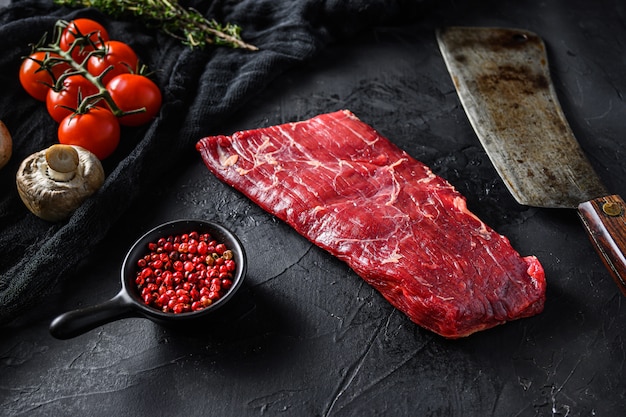 Bavette steak near butcher knife with pink pepper and rosemary