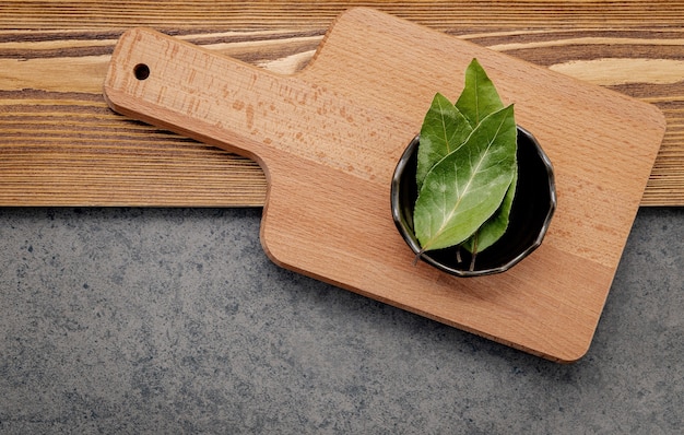 The bay leaves in ceramic bowl on shabby wooden