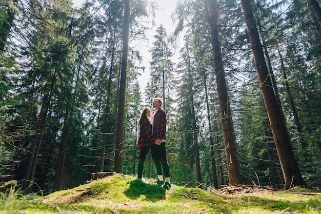 Bbeautiful couple of hipsters in love stands in a beautiful untouched forest and hugs