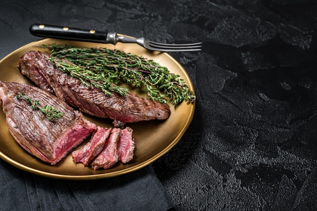 BBQ grilled Bavette Bavet beef meat steak with herbs on a plate Black background Top view Copy space