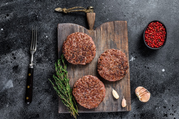 BBQ grilled beef meat patties for burger from mince meat and herbs on a wooden board