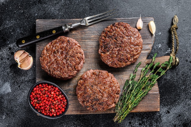 BBQ grilled beef meat patties for burger from mince meat and herbs on a wooden board