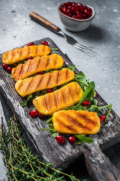 BBQ Grilled Halloumi cheese with arugula on wooden board. Gray background. Top view.