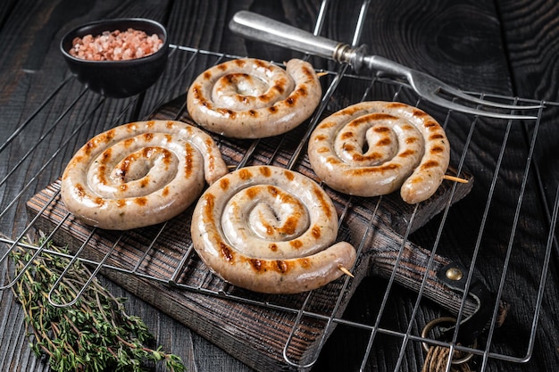 BBQ grilled spiral pork meat sausages on a grill Black background Top view