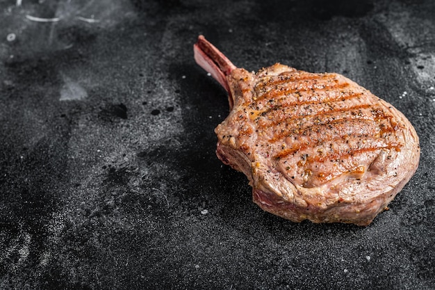 BBQ Grilled Tomahawk beef veal steak on butcher table Black background Top view Copy space