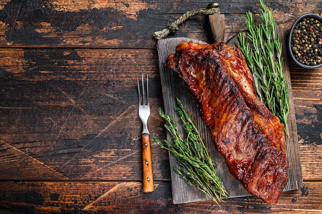 BBQ grilled veal calf brisket meat on short spare rib on wooden cutting board.