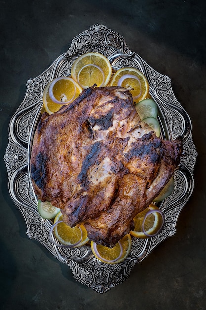 BBQ mutton ribs with onion and lemon slice served in dish isolated on dark background top view