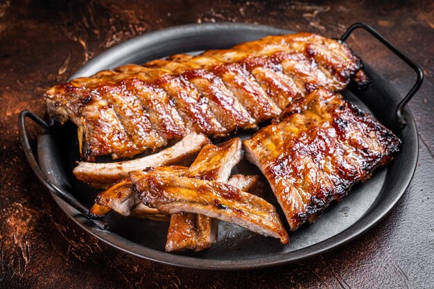 BBQ pork spare ribs St Louis with hot honey marinade in a steel tray Dark background Top view