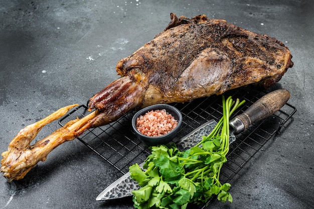 BBQ Roasted lamb mutton leg with herbs and spices on a grill Black background Top view