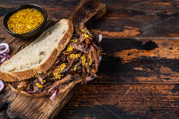 BBQ Sandwich with slow roasted pulled pork meat. Dark wooden background. Top view. Copy space.