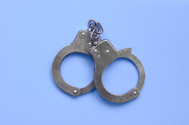 Bdsm and sex games concept. Handcuffs on blue background