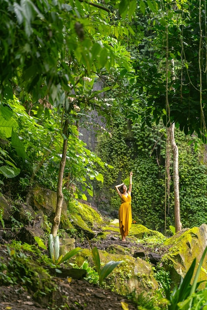 Be happy. Relaxed brunette girl standing on stones while posing on camera, enjoying tropical views