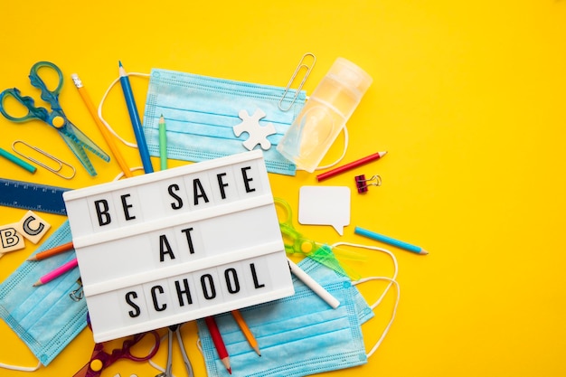 Be safe at school message with school equipment and covid masks