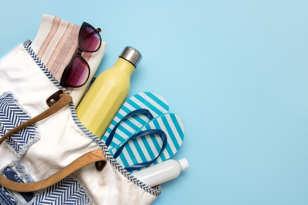 Beach accessories in a beach bag on a blue background with copy space