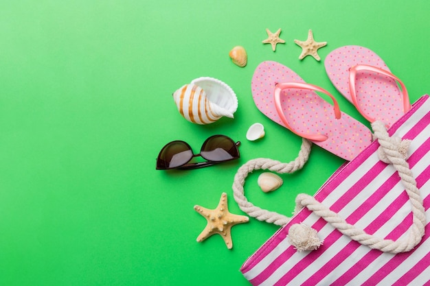 Beach accessories flat lay top view on colored background Summer travel concept Bag with starfish and sea shell Top view