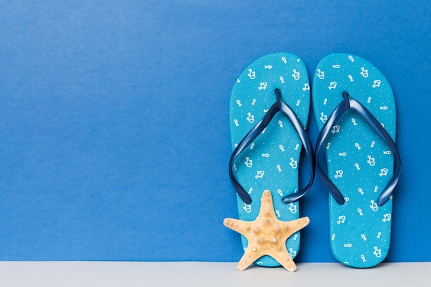 Beach accessories Flip flops and starfish on colored background Mock up with copy space