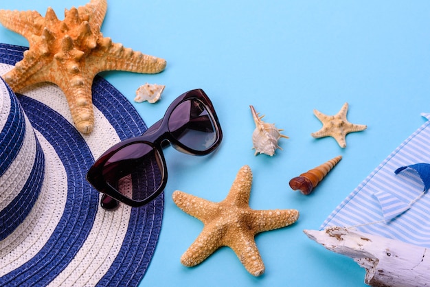 Beach accessories: glasses and hat with shells and sea stars. Summer background