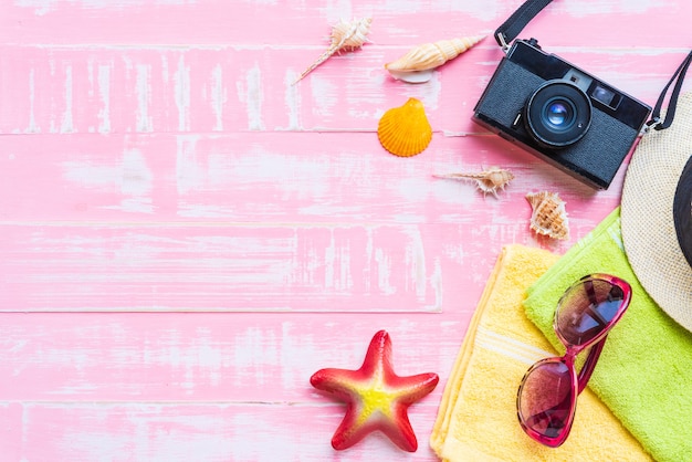 Beach accessories on pink pastel wooden background for summer concept.