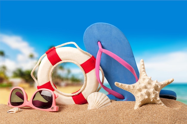 Beach accessories on sand. Flip flops, sea star, lifebuoy