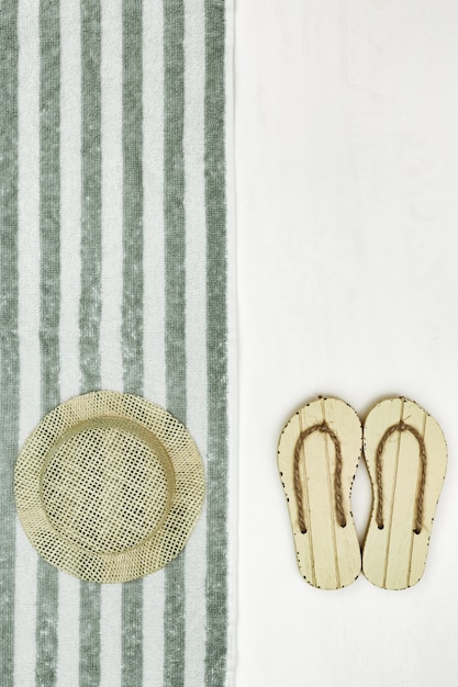 Beach accessories. Summer shoes - flip-flops, sunhat, cotton towel. Minimalism style. Summer flat lay. Copy space.