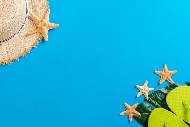 Beach accessories with straw hat and seashells on blue